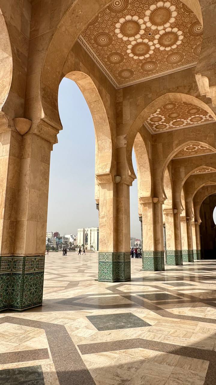 Stone arches of Hassan II Mosque colonnade frame view of Casablanca skyline
