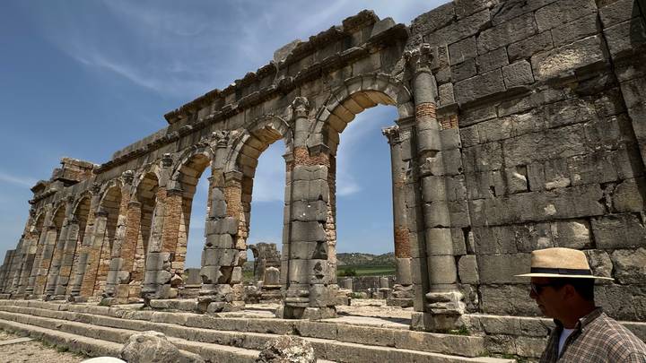 Partially preserved Roman stone arches of Volubilis with visitor in hat