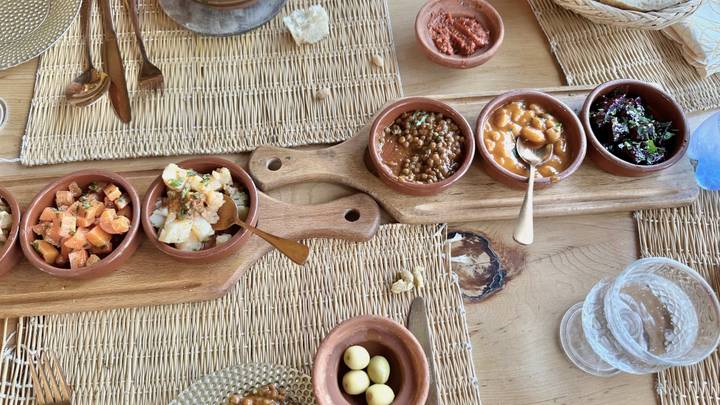 Rustic wooden table topped with assorted Moroccan salads and mezze dishes