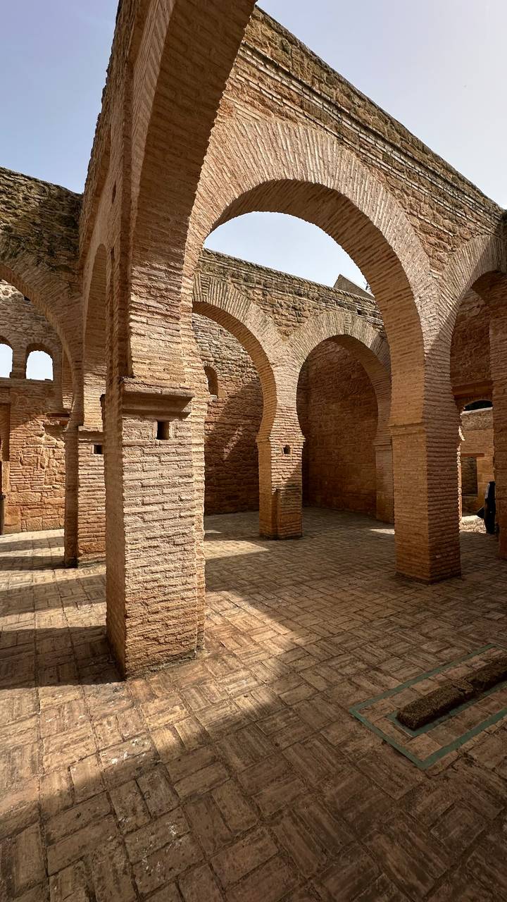 Warm light illuminates brick arches and pillars inside an ancient mosque ruin