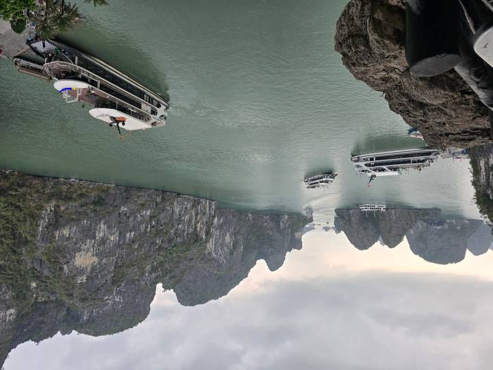 Tour boats cruise between towering limestone islands in the emerald waters of Halong Bay.