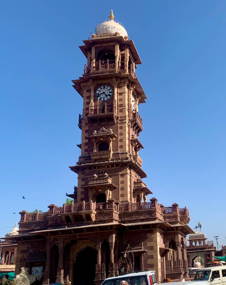 Historic sandstone clock tower rises into clear blue sky in Jodhpur