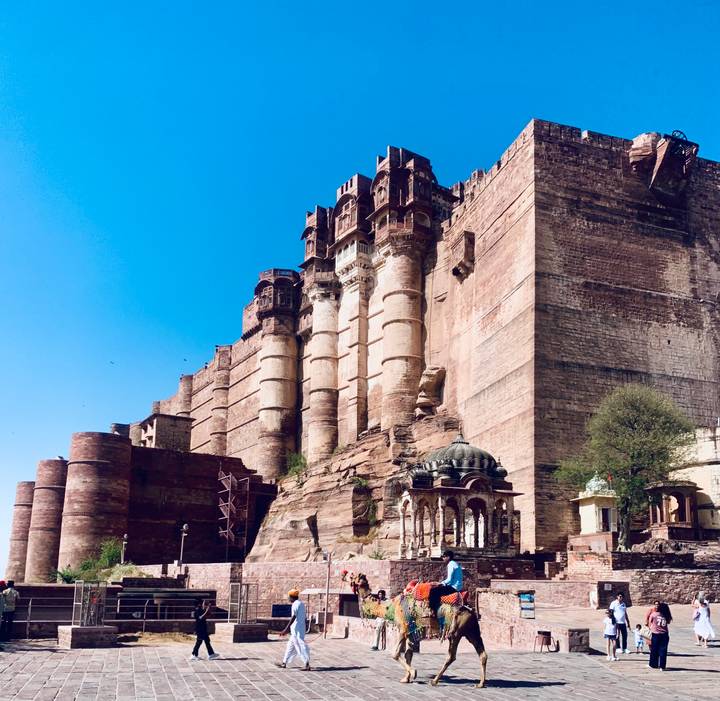 Massive red sandstone walls of Mehrangarh Fort rise majestically above city
