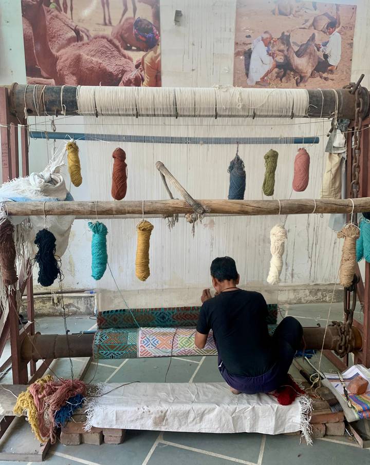 Craftsman weaves colorful carpet threads on a traditional loom