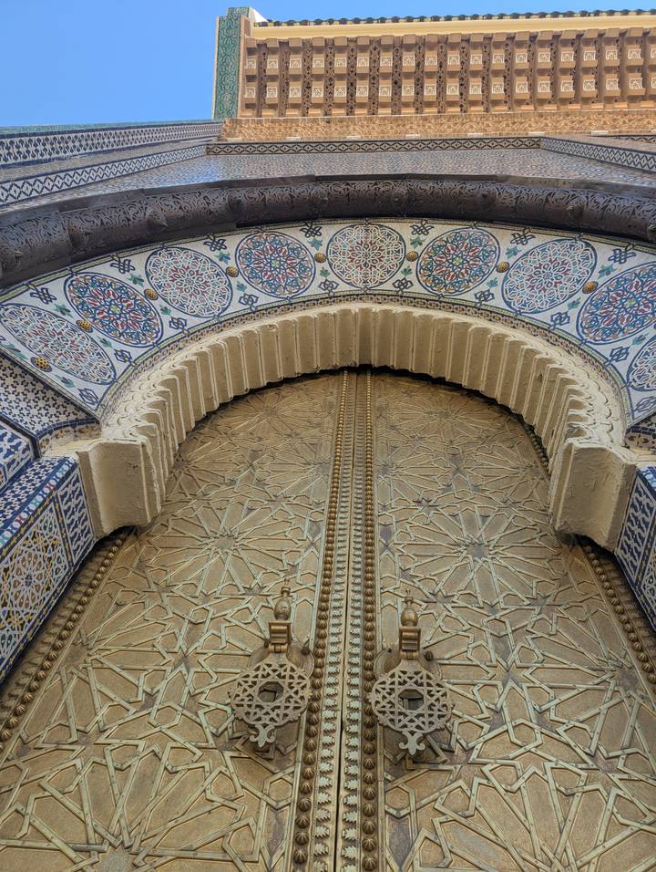 Intricately carved and tiled arched doorway of a Moroccan building shot from below.