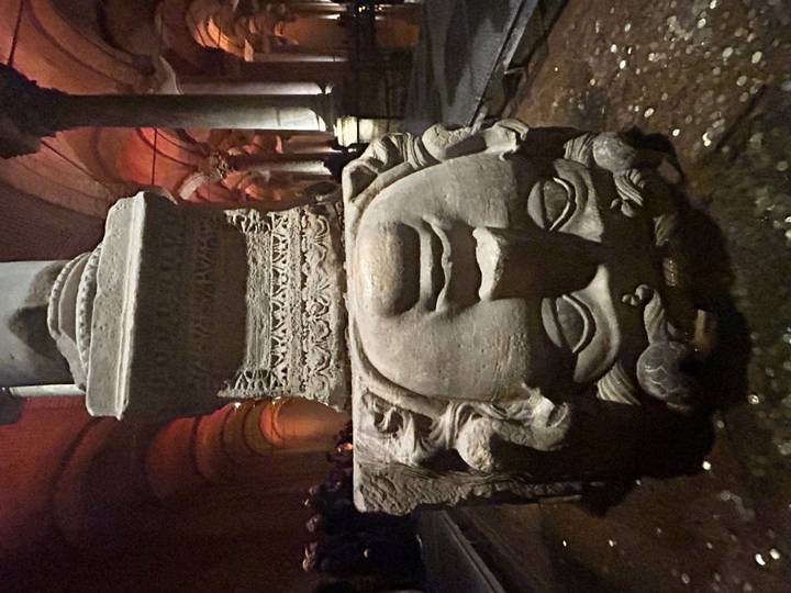 Close-up of the upside-down Medusa head base in the dimly lit Basilica Cistern.
