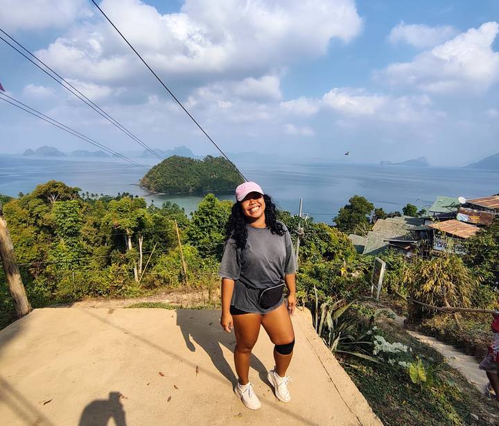 Smiling traveller posing at a viewpoint over tropical islands and sea.