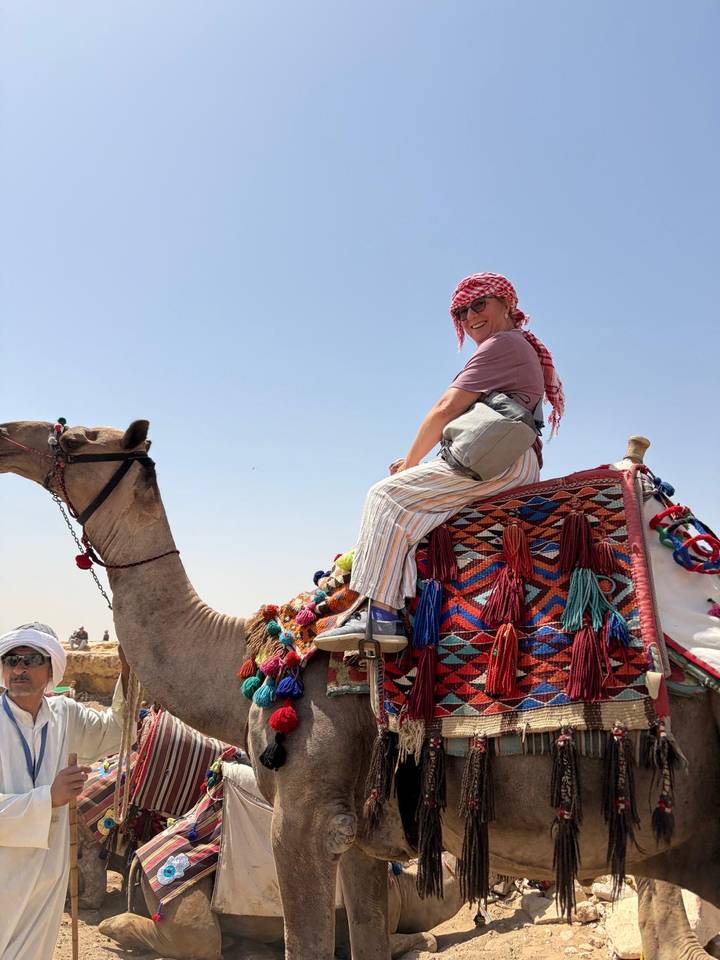 Woman riding a decorated camel in the desert under a clear blue sky
