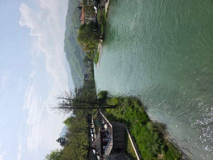 Calm green river flowing through valley with wooded hills and distant town