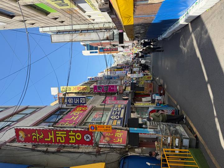 Lively Korean street packed with colourful shop signs and pedestrians.