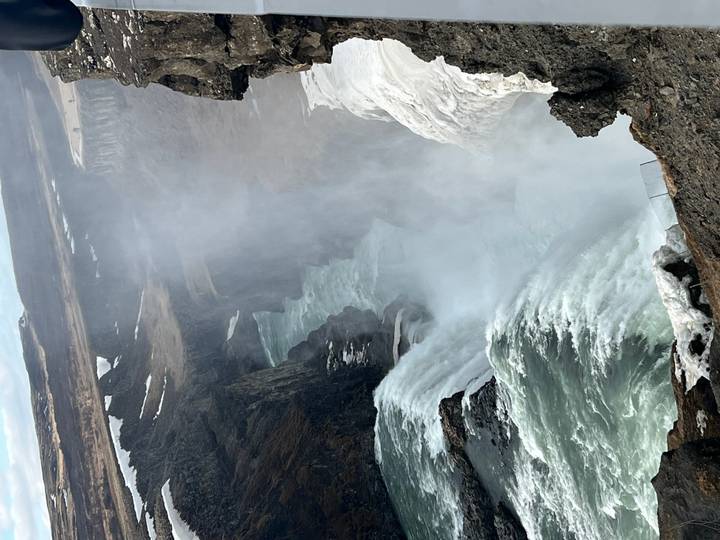 Powerful Gullfoss waterfall cascades into a mist-filled canyon amid snowy edges.