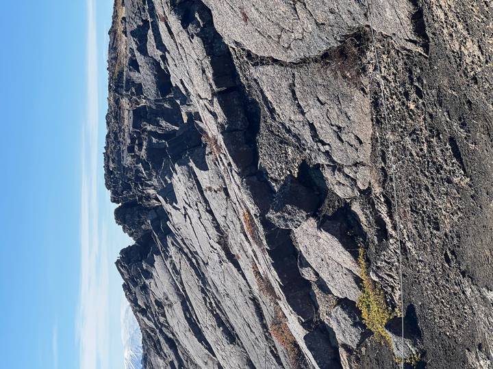 Jagged dark lava rocks and fissures dominate a barren volcanic landscape.