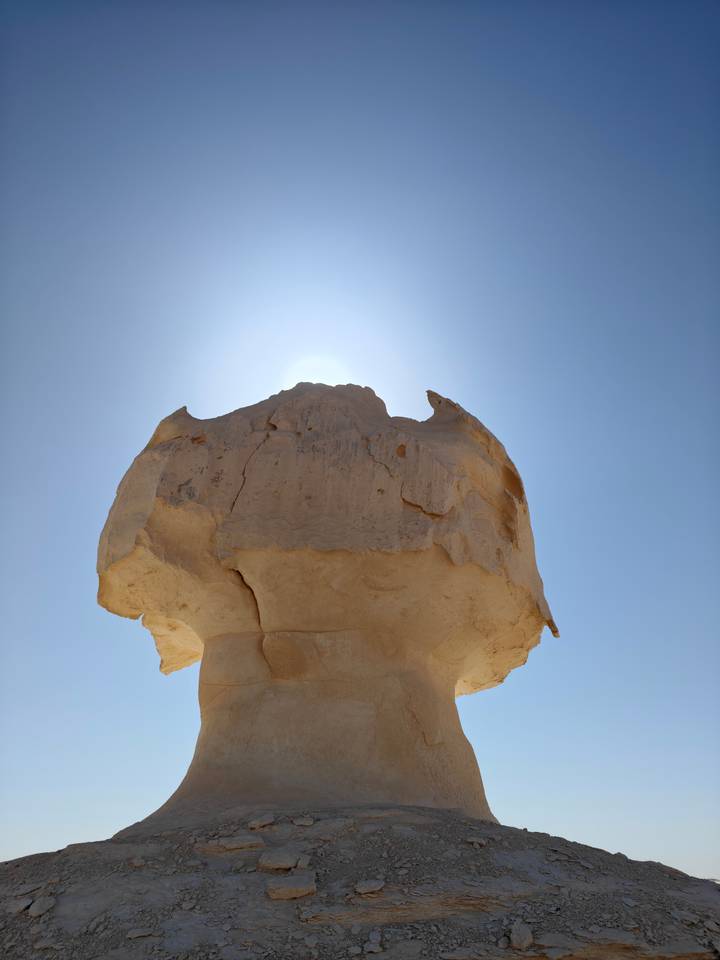 Close view of a mushroom-shaped white rock lit by high midday sun in the desert