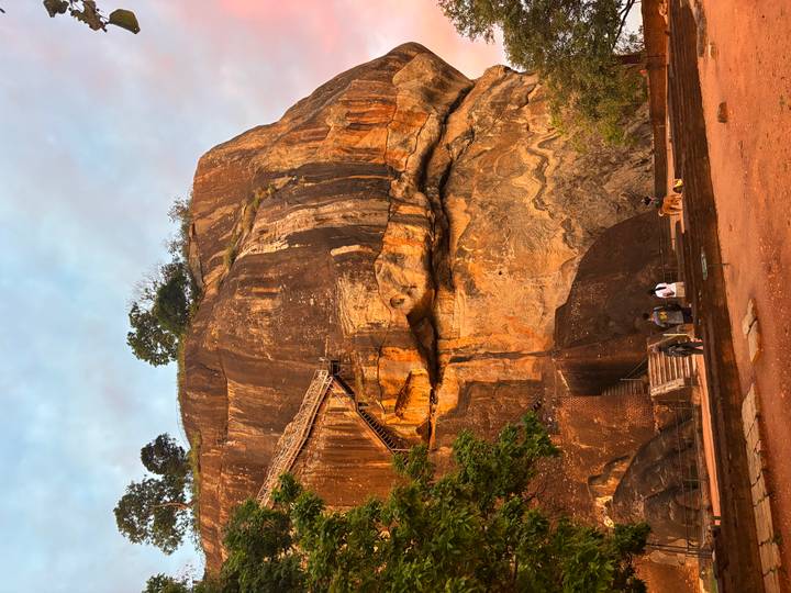Massive orange rock fortress with steep staircase glowing in soft dawn light