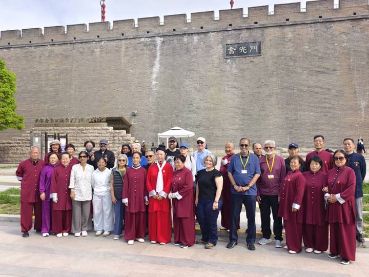 Large tour group posing in front of ancient city wall gate