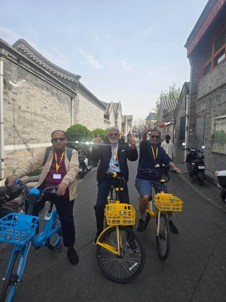 Friends riding yellow rental bikes through a historic hutong alley