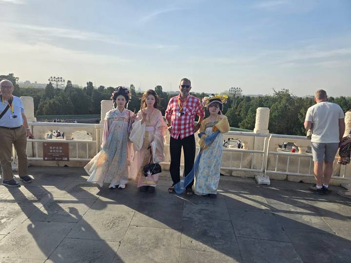Tourist posing with costumed locals on a viewpoint overlooking a park