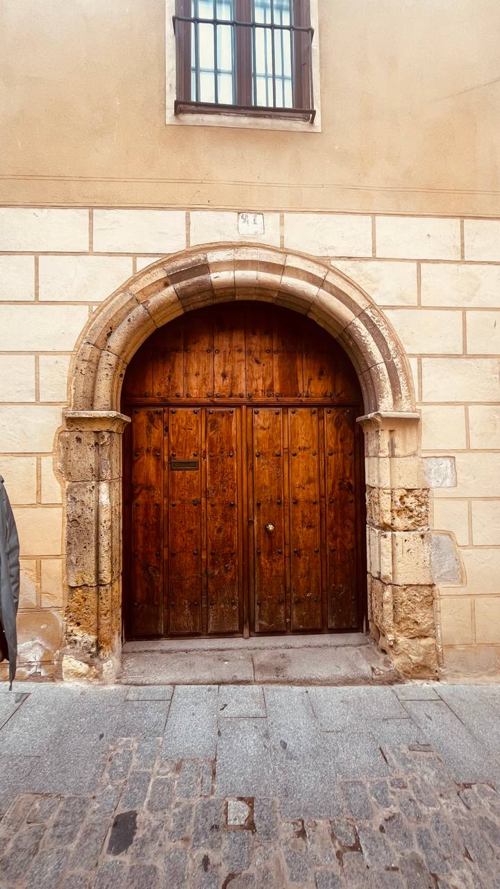 Close-up of an old wooden double door set within a stone archway.
