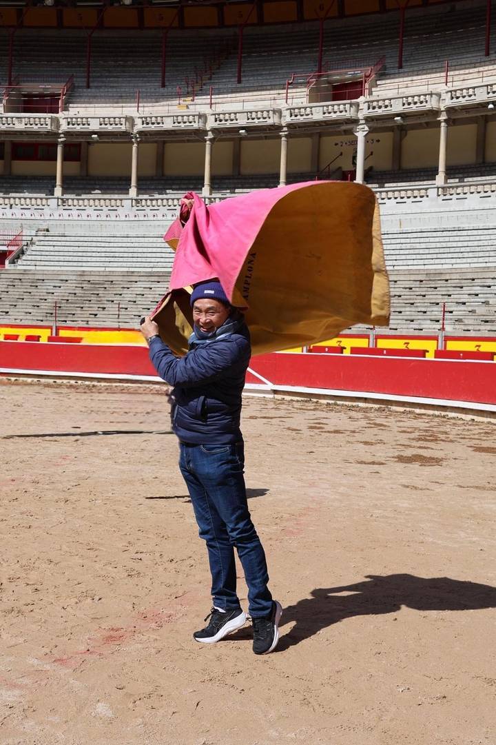 Visitor playfully waves a bullfighting cape inside Pamplona's empty arena.