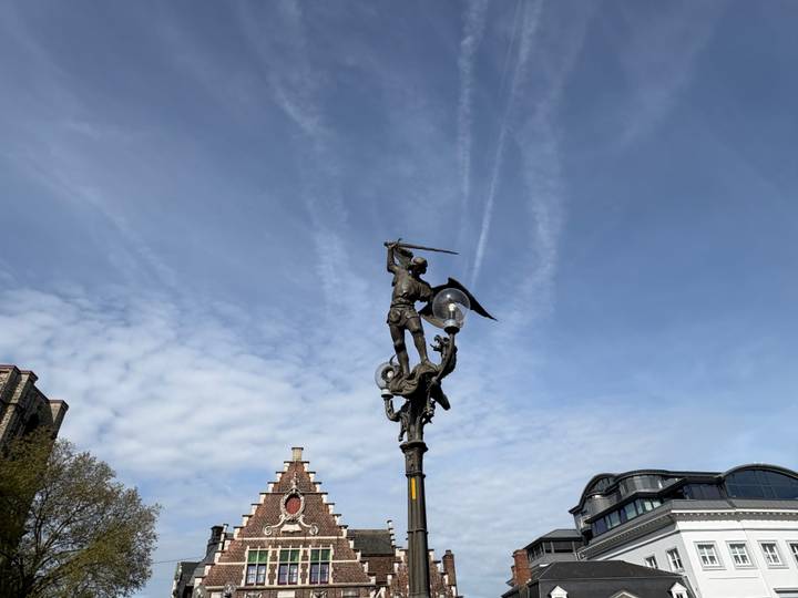Statue of an angel brandishing a sword atop a lamp post silhouetted against a streaked blue sky