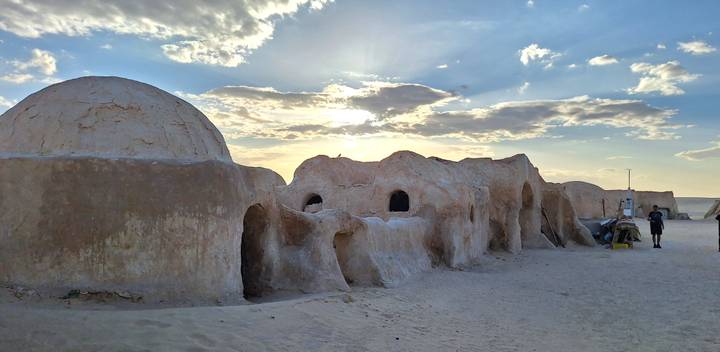 Adobe domes and arched structures of the Star Wars Mos Espa set silhouetted by a setting sun.