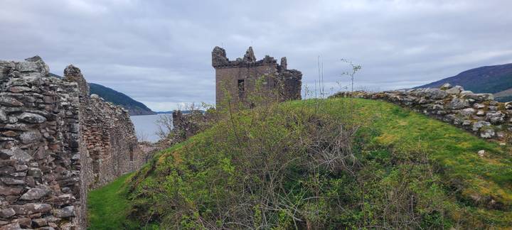 Ruined walls of Urquhart Castle overlooking Loch Ness beneath an overcast sky.