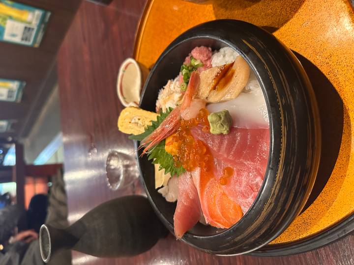 Colorful chirashi sushi bowl topped with fresh sashimi, roe, and garnishes on a lacquer tray.