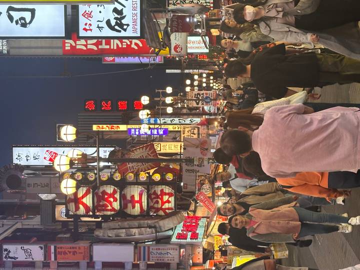 Bustling night scene along Osaka’s Dotonbori street filled with neon signs and crowds.