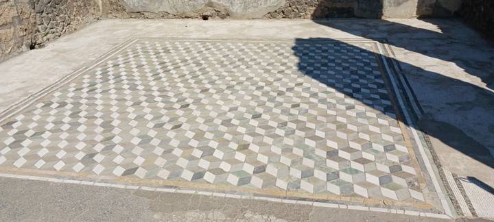 Stone mosaic floor in a 3-D cube pattern at an outdoor archaeological site.