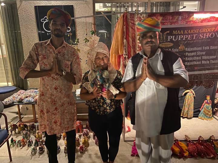 Traveler poses with two local performers at a nighttime Rajasthani puppet show.