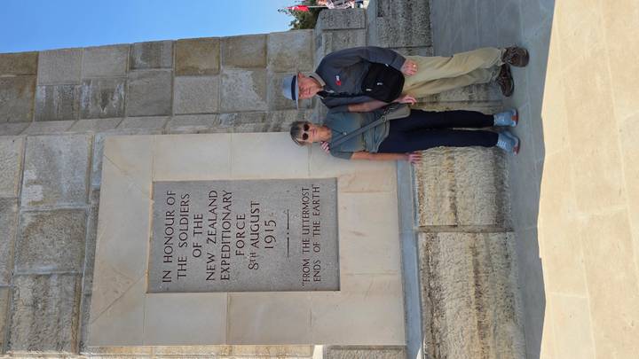Older couple stands beside a stone memorial tablet honoring New Zealand soldiers at Gallipoli.