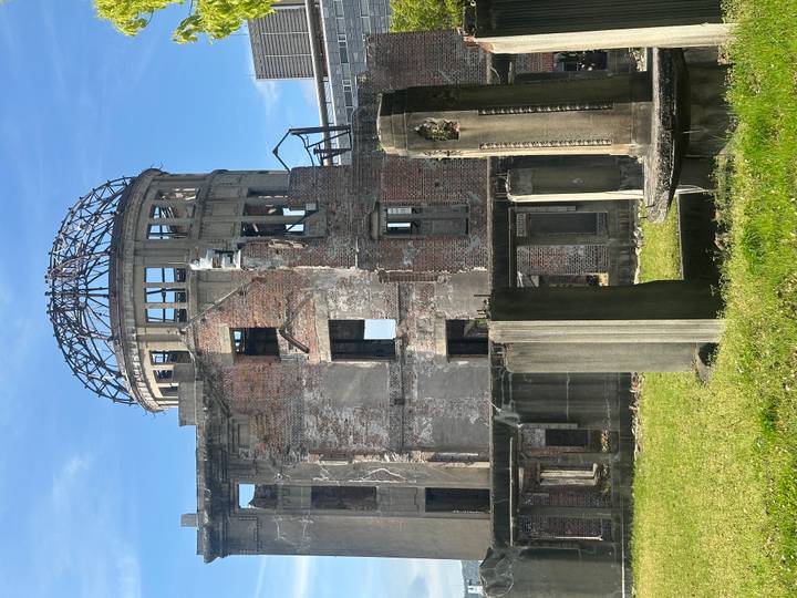 Ruined red-brick Atomic Bomb Dome stands solemnly beneath blue sky.