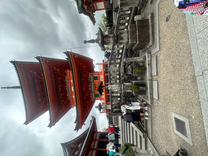 Tall vermilion pagoda towers above visitors at famous hillside temple.