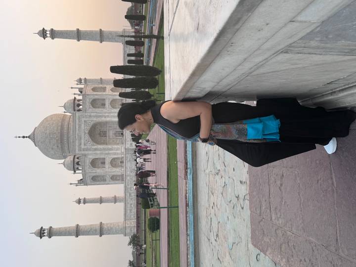 Traveler leaning on a marble railing with the Taj Mahal softly lit behind.