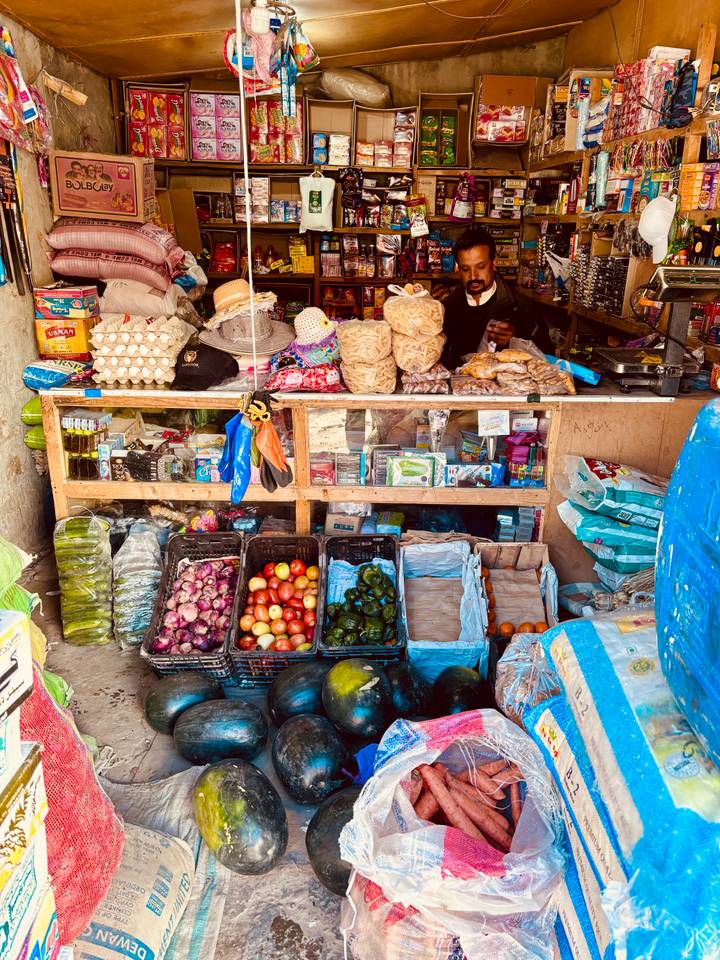 Small local shop stall displaying fresh produce, snacks, and household items.