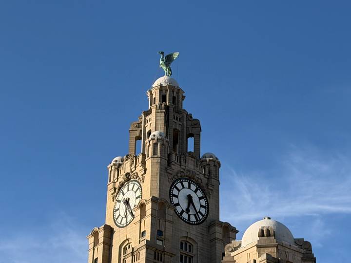 Clock tower of the Royal Liver Building topped by the Liver Bird against a clear blue sky.