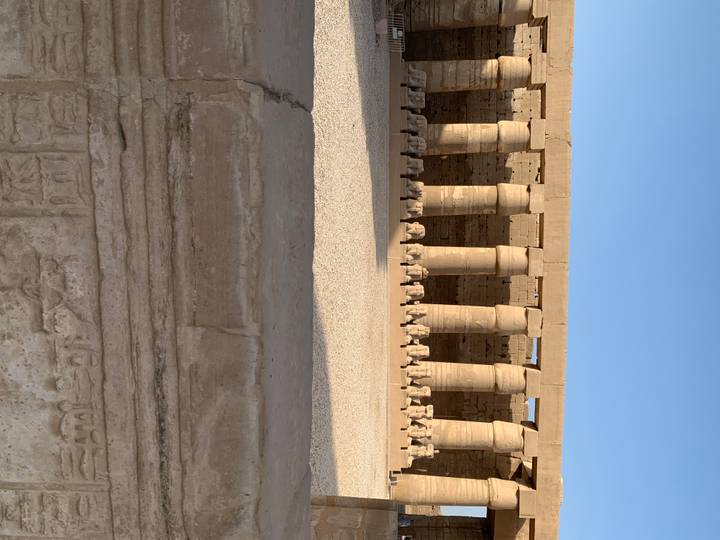 Ram-headed sphinx colonnade and massive pillars inside an Egyptian temple.