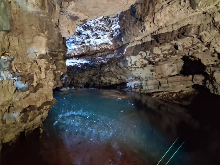 Dimly lit cave pool sparkles with reflections beneath rugged limestone walls.