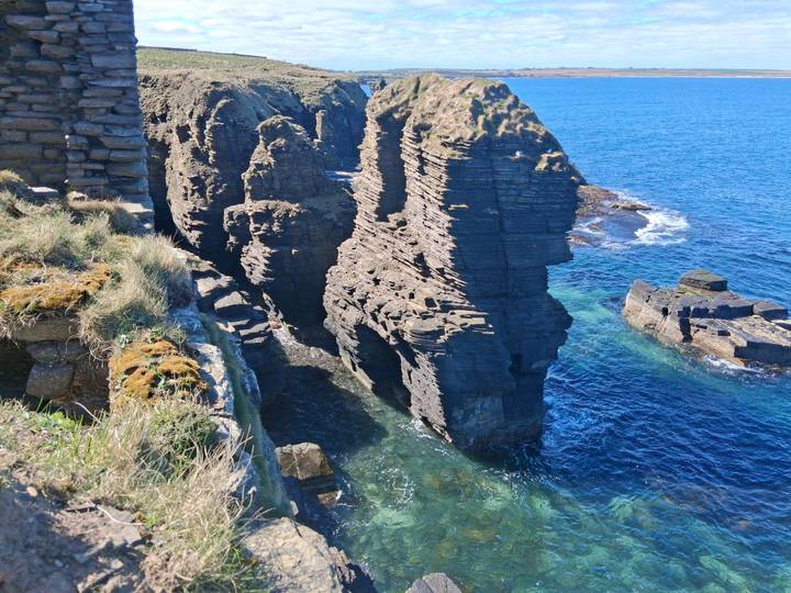 Sheer grey sea cliffs drop into vivid turquoise waters along Scotland’s dramatic coastline.
