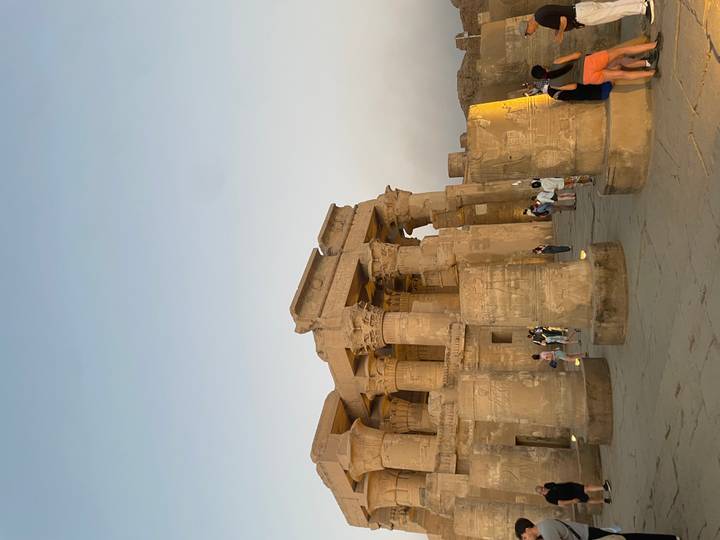 Evening light bathes the massive sandstone columns of Kom Ombo Temple as visitors explore.