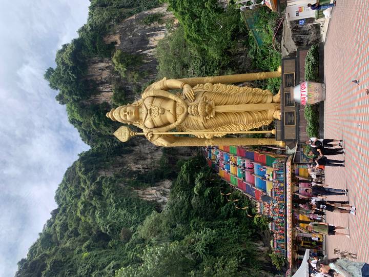 Crowds ascend the colorful steps toward the giant golden statue at Batu Caves.