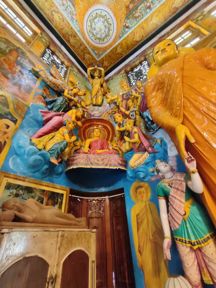 Vibrant temple interior with colourful statues of Buddha surrounded by celestial attendants.