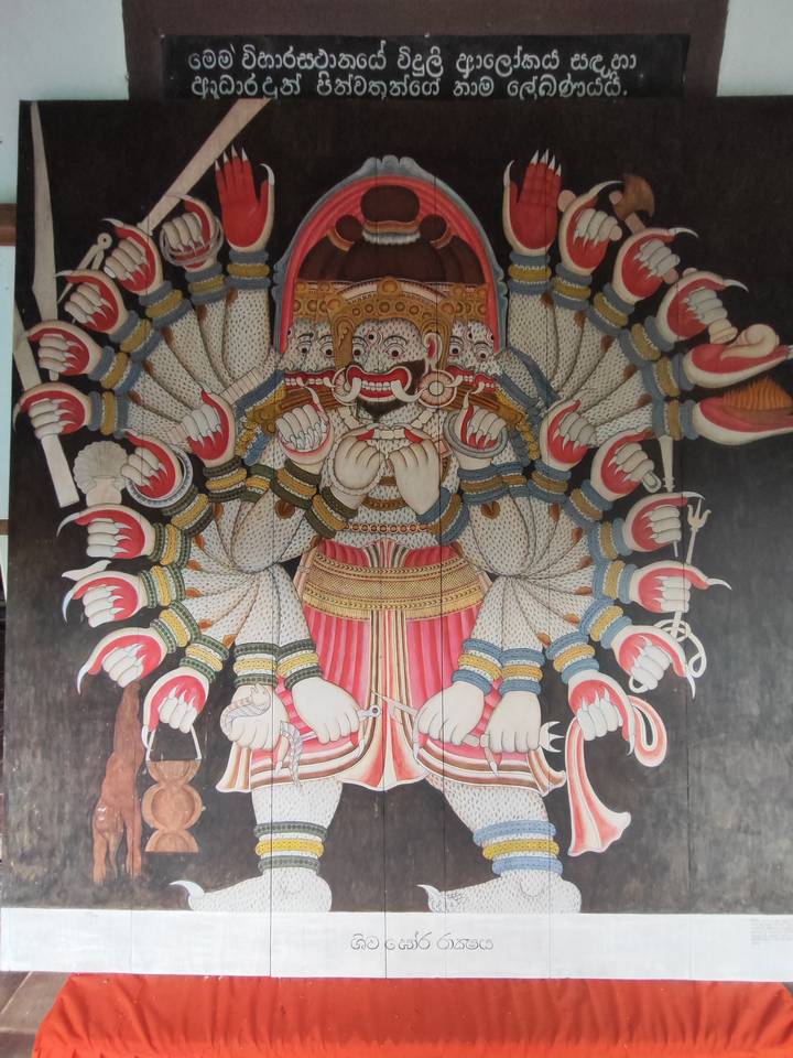 Detailed mural of a many-headed demon king holding weapons, rich in traditional Sri Lankan art style.
