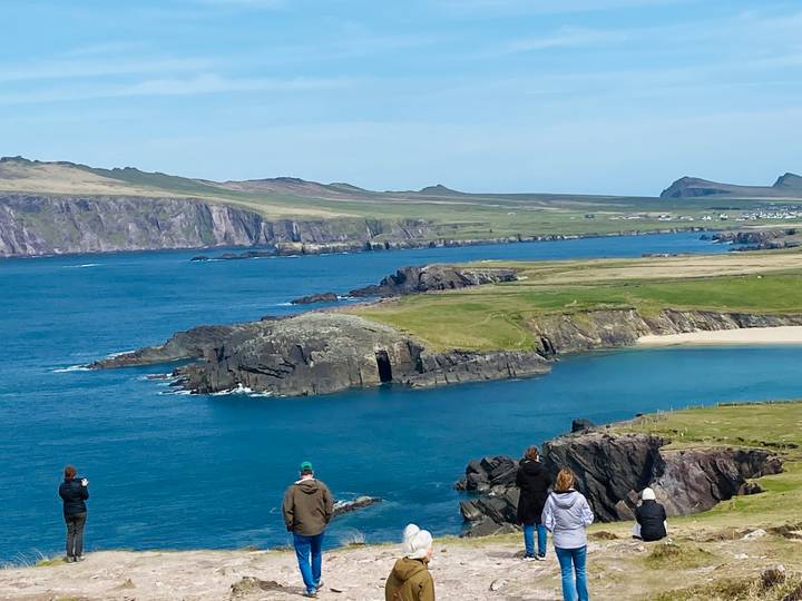 Sweeping coastal cliffs and turquoise sea at Slea Head with visitors admiring the view.