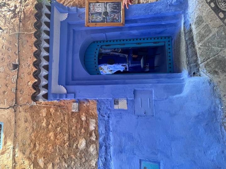 Vivid blue doorway and wall in the medina of Chefchaouen with rustic stone textures.
