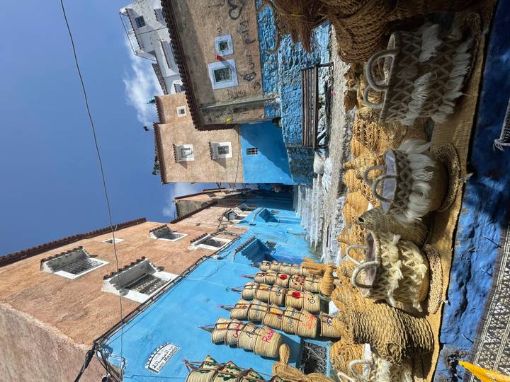 Colourful blue alley of Chefchaouen with woven baskets and steep stone steps leading upward.