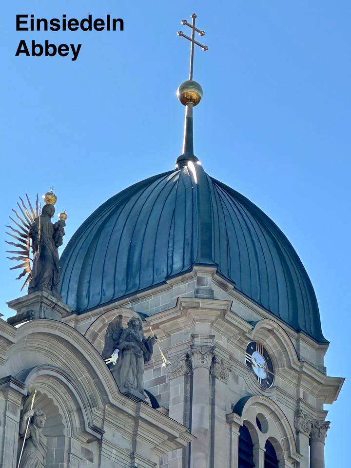 Close-up of a blue domed church roof with a statue against a clear sky.