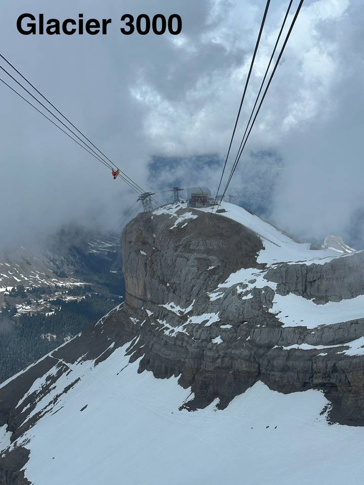 A snowy alpine peak with cable cars ascending through mist to a mountaintop station.