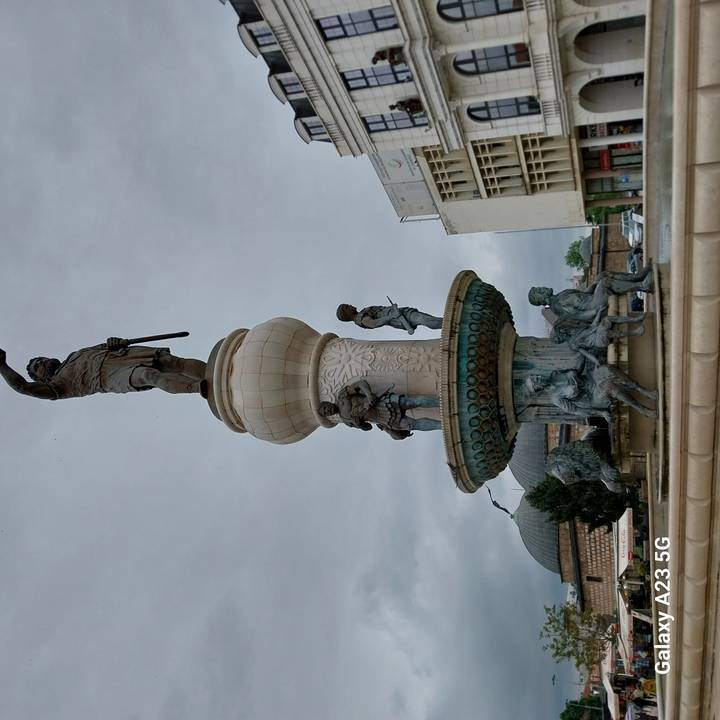 Tall fountain crowned by a heroic bronze figure with subsidiary statues around its base.