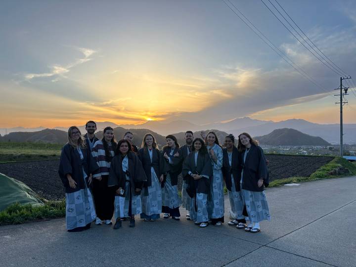 Group wearing traditional yukata posing at sunset with mountain silhouette in the background.